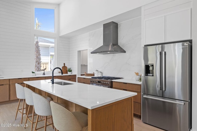 1100 S Sixth St, Carolina Beach, NC 28428 - kitchen with appliances with stainless steel finishes, wall chimney range hood, a sink, light wood-type flooring, and decorative backsplash