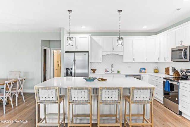 822 S Topsail Dr Unit B, Surf City, NC 28445 - kitchen with stainless steel appliances, a sink, light wood-style flooring, tasteful backsplash, and a kitchen breakfast bar