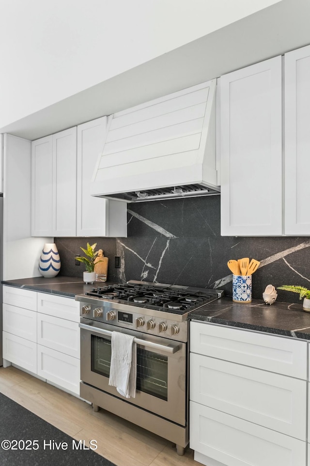 609 Augusta Ave, Carolina Beach, NC 28428 - kitchen featuring stainless steel gas range, custom range hood, white cabinetry, and backsplash
