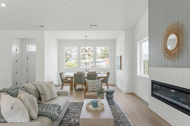 609 Augusta Ave, Carolina Beach, NC 28428 - living room with light wood finished floors, a chandelier, a glass covered fireplace, and baseboards