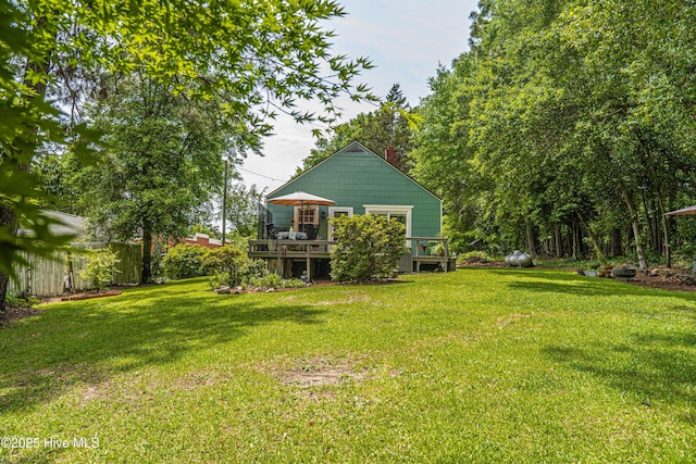 view of green lawn with a wooden deck