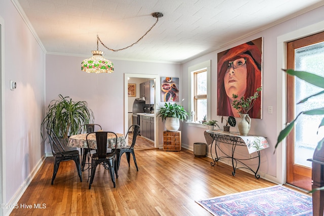 dining room featuring crown molding, light wood finished floors, and baseboards