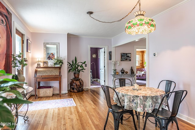 dining room featuring wood finished floors, crown molding, and baseboards