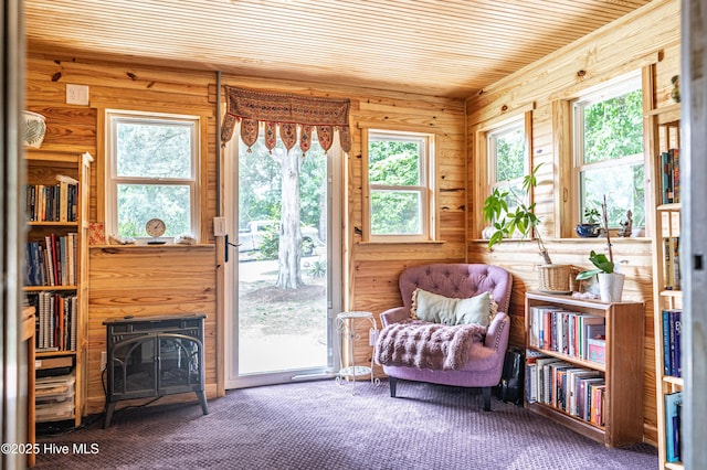living area with wooden walls, a fireplace, wood ceiling, and carpet flooring