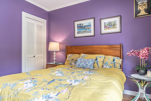 bedroom featuring a closet, crown molding, baseboards, and wood finished floors