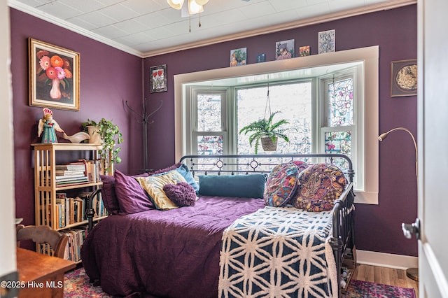 bedroom with wood finished floors, ornamental molding, and baseboards