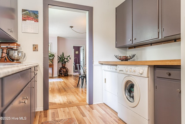 clothes washing area with separate washer and dryer and light wood-style flooring