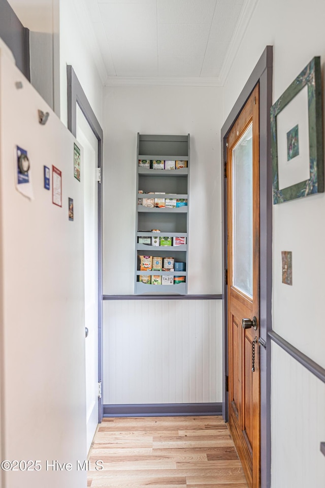 hallway with crown molding, wood finished floors, and wainscoting