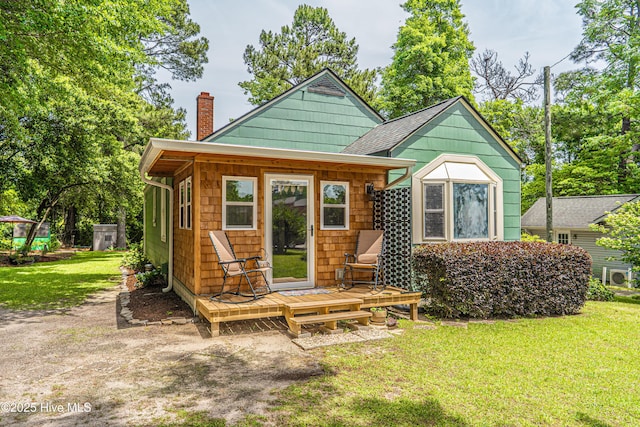 rear view of property with a chimney, a yard, and a deck