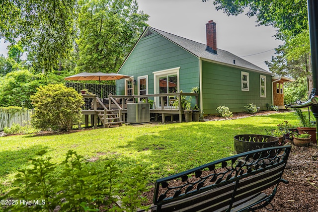 back of property featuring a chimney, central AC unit, a wooden deck, and a shingled roof