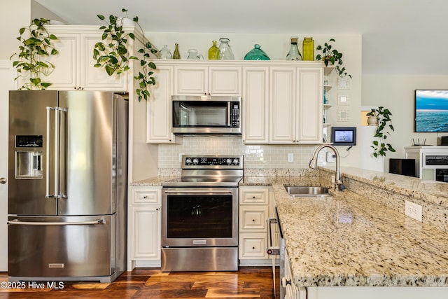 104 NE 63rd St, Oak Island, NC 28465 - kitchen with appliances with stainless steel finishes, a sink, a peninsula, dark wood finished floors, and light stone counters