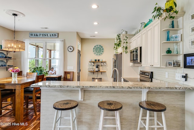 104 NE 63rd St, Oak Island, NC 28465 - kitchen with stainless steel appliances, open shelves, a chandelier, light stone counters, and recessed lighting