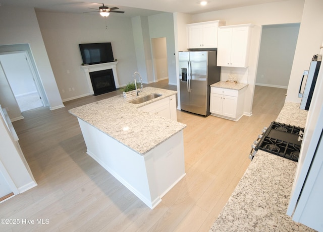 9308 Little Osprey Dr, Calabash, NC 28467 - kitchen with stainless steel fridge, ceiling fan, a fireplace with flush hearth, light wood-type flooring, and white cabinets
