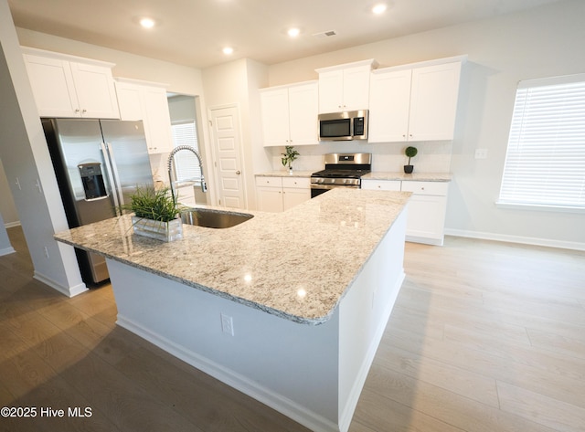 9308 Little Osprey Dr, Calabash, NC 28467 - kitchen with stainless steel appliances, light wood finished floors, a large island, white cabinetry, and recessed lighting