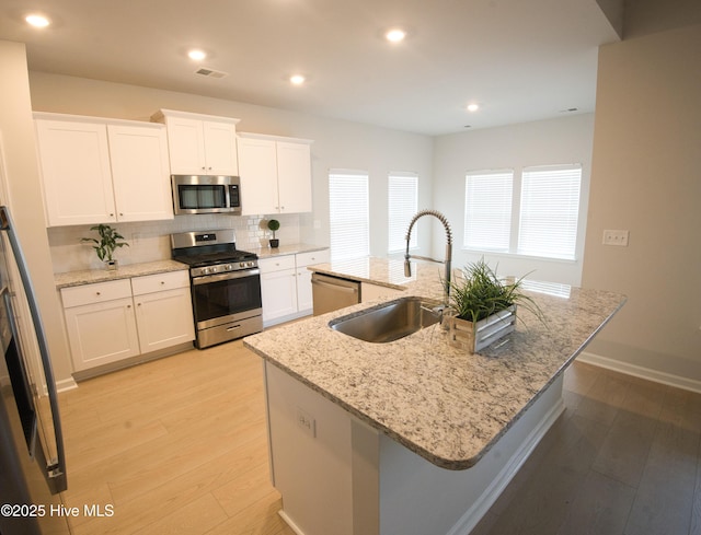 9308 Little Osprey Dr, Calabash, NC 28467 - kitchen featuring appliances with stainless steel finishes, tasteful backsplash, light wood-style floors, an island with sink, and recessed lighting