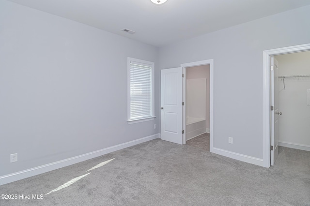 1707 N Carolina St, Goldsboro, NC 27530 - unfurnished bedroom with a walk in closet, carpet floors, baseboards, and a closet