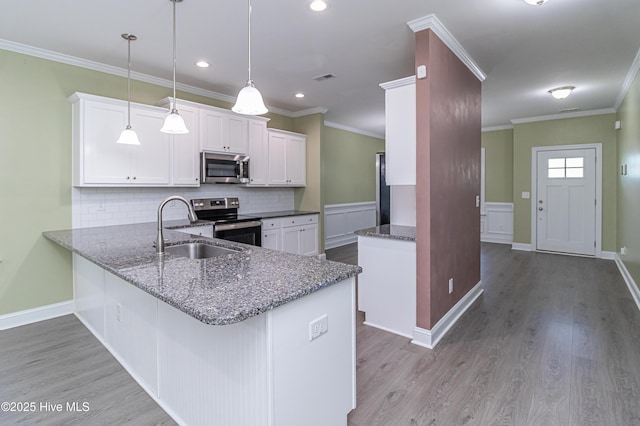1707 N Carolina St, Goldsboro, NC 27530 - kitchen with appliances with stainless steel finishes, a sink, tasteful backsplash, white cabinetry, and wood finished floors