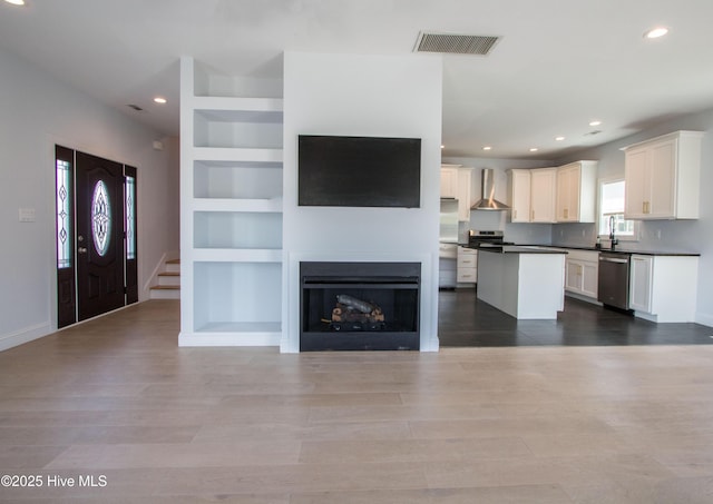 302 N 16th St, Morehead City, NC 28557 - kitchen with wall chimney exhaust hood, appliances with stainless steel finishes, open floor plan, built in features, and dark countertops