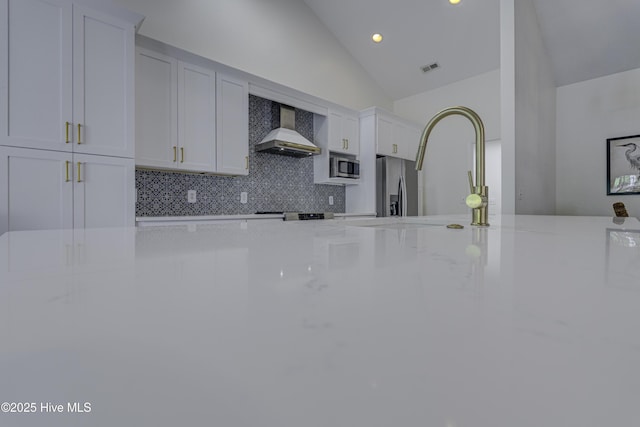 302 Gaskins Ln, Wilmington, NC 28411 - kitchen with wall chimney range hood, appliances with stainless steel finishes, backsplash, vaulted ceiling, and light stone countertops