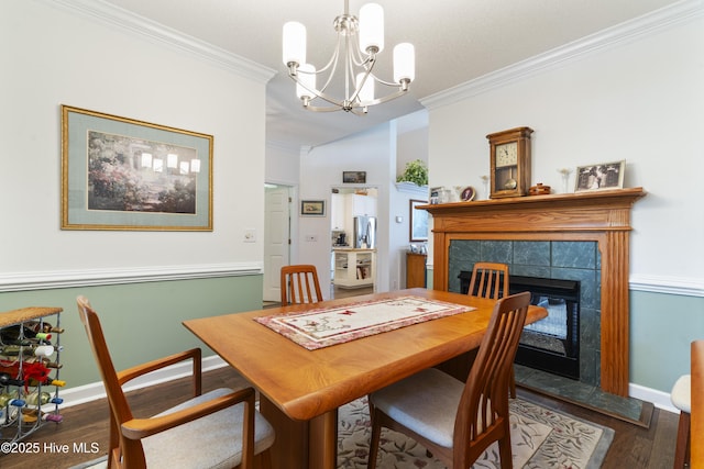308 Crooked Gulley Cir, Sunset Beach, NC 28468 - dining space featuring crown molding, a chandelier, wood finished floors, a tiled fireplace, and vaulted ceiling