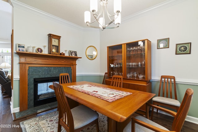 308 Crooked Gulley Cir, Sunset Beach, NC 28468 - dining area featuring crown molding, a chandelier, wood finished floors, a tiled fireplace, and a wainscoted wall