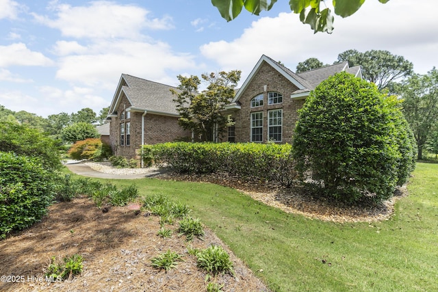 308 Crooked Gulley Cir, Sunset Beach, NC 28468 - view of side of home featuring brick siding, roof with shingles, and a yard