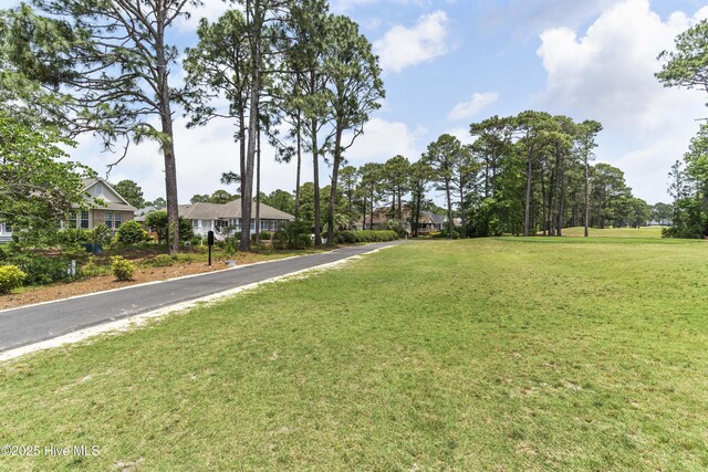 308 Crooked Gulley Cir, Sunset Beach, NC 28468 - view of green lawn with asphalt driveway