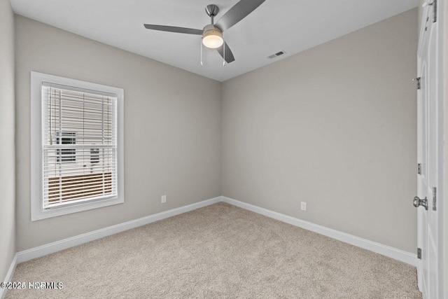 carpeted spare room featuring baseboards and ceiling fan