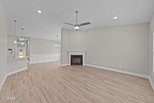 unfurnished living room featuring light wood-style floors, a fireplace, a ceiling fan, a sink, and recessed lighting