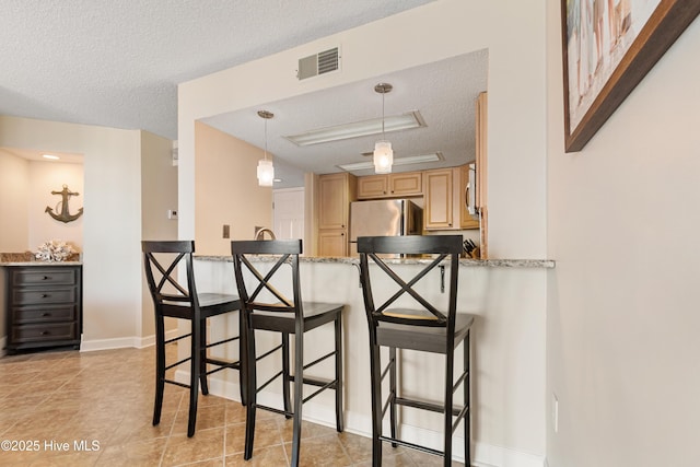 2000 New River Inlet Rd Unit 3113, North Topsail Beach, NC 28460 - kitchen with freestanding refrigerator, a textured ceiling, a kitchen bar, light brown cabinets, and a peninsula