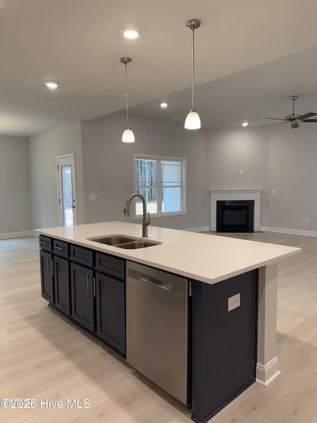 kitchen featuring stainless steel dishwasher, a sink, an island with sink, open floor plan, and light wood-style flooring
