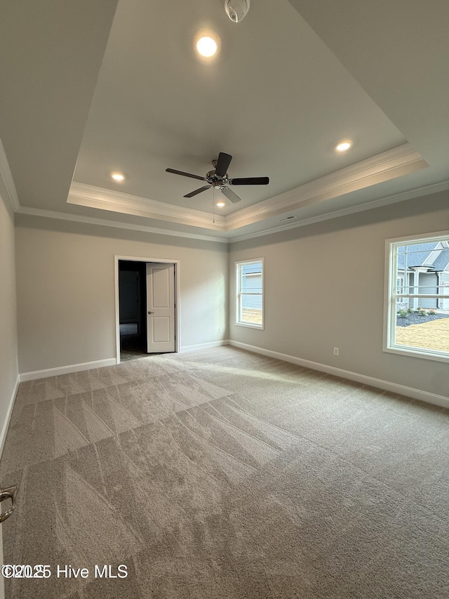 carpeted empty room with a tray ceiling, ornamental molding, baseboards, and recessed lighting