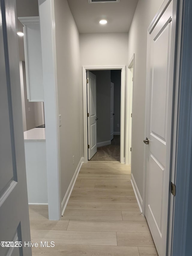 corridor featuring light wood finished floors, baseboards, and recessed lighting