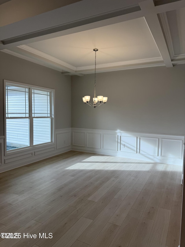 unfurnished dining area featuring ornamental molding, a chandelier, beamed ceiling, a decorative wall, and wainscoting