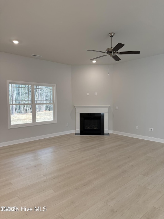 unfurnished living room with ceiling fan, recessed lighting, light wood-style floors, a fireplace with flush hearth, and baseboards