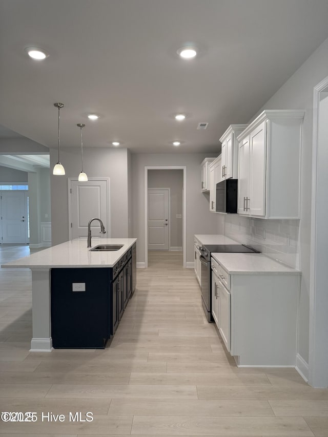 kitchen featuring stainless steel range with electric stovetop, a sink, baseboards, light countertops, and recessed lighting