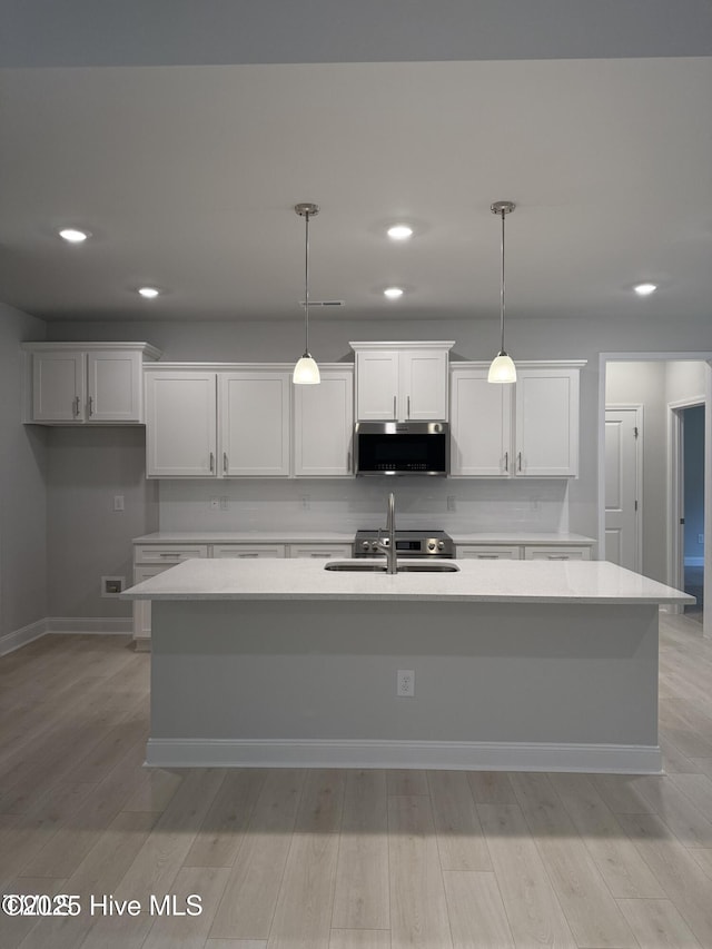 kitchen featuring appliances with stainless steel finishes, a sink, recessed lighting, white cabinetry, and light countertops