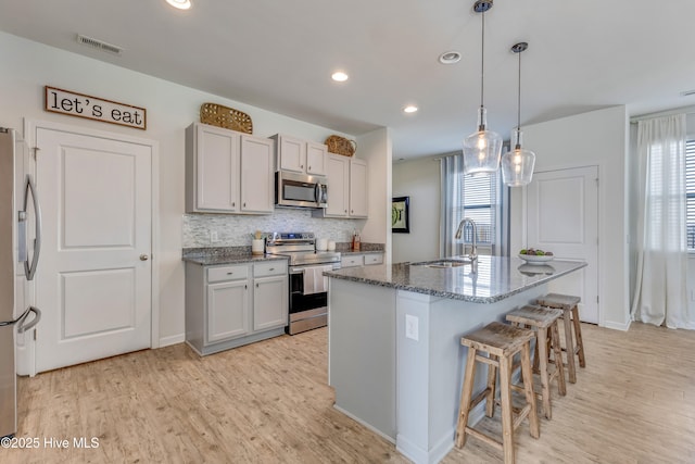 815 Avington Ln NE, Leland, NC 28451 - kitchen featuring appliances with stainless steel finishes, a sink, light wood-style flooring, a breakfast bar, and recessed lighting