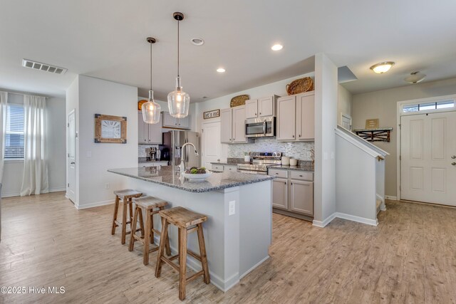 815 Avington Ln NE, Leland, NC 28451 - kitchen with appliances with stainless steel finishes, a kitchen breakfast bar, backsplash, light wood-style floors, and baseboards