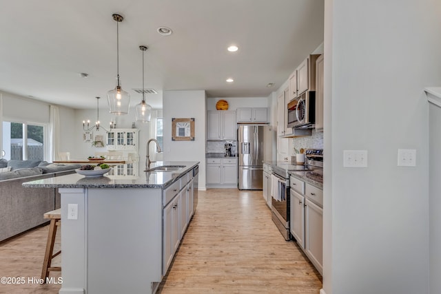 815 Avington Ln NE, Leland, NC 28451 - kitchen featuring stainless steel appliances, a sink, a breakfast bar area, tasteful backsplash, and light wood-style flooring