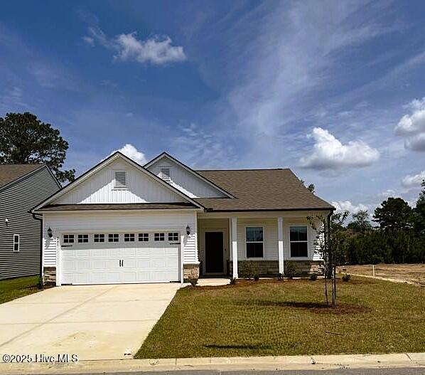 241 Eagle Claw Dr Unit 4014, Carolina Shores, NC 28467 - craftsman-style house with driveway, an attached garage, stone siding, a front lawn, and covered porch