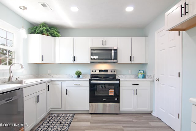 1 Willetts Dr, Southport, NC 28461 - kitchen with stainless steel appliances, white cabinetry, recessed lighting, light countertops, and light wood-style floors