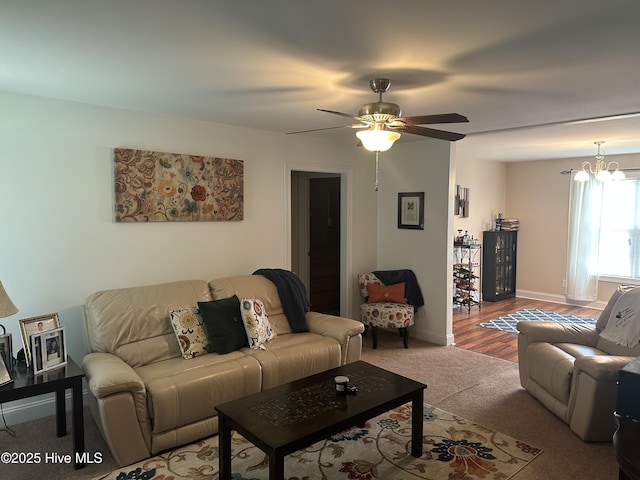 living room featuring light carpet, a chandelier, a ceiling fan, and baseboards