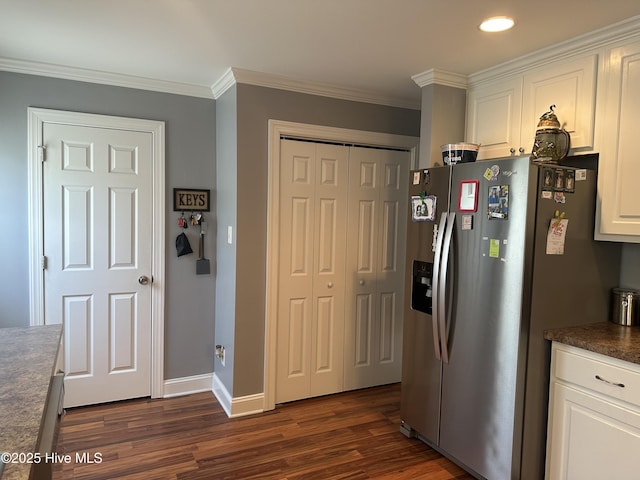 kitchen with stainless steel fridge, dark wood-type flooring, white cabinetry, crown molding, and dark countertops
