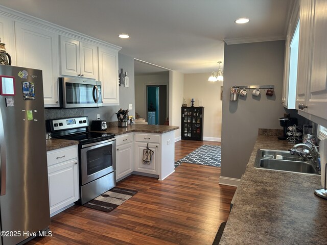 kitchen with stainless steel appliances, a sink, dark wood-style flooring, a peninsula, and dark countertops