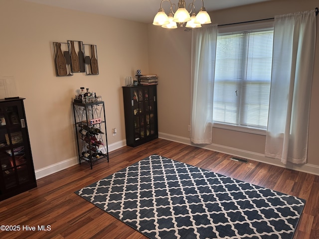 sitting room with a chandelier, baseboards, and dark wood-style flooring