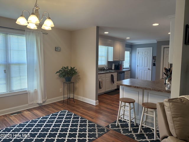 kitchen with a sink, dishwasher, dark wood-type flooring, dark countertops, and baseboards