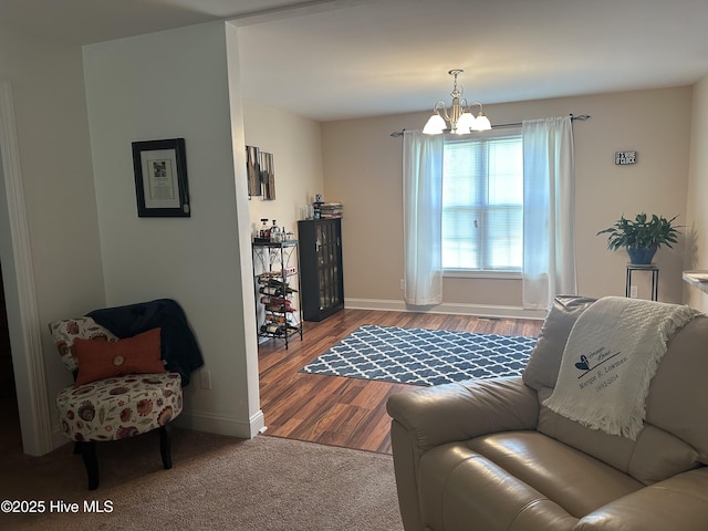 living room featuring a chandelier, baseboards, and wood finished floors