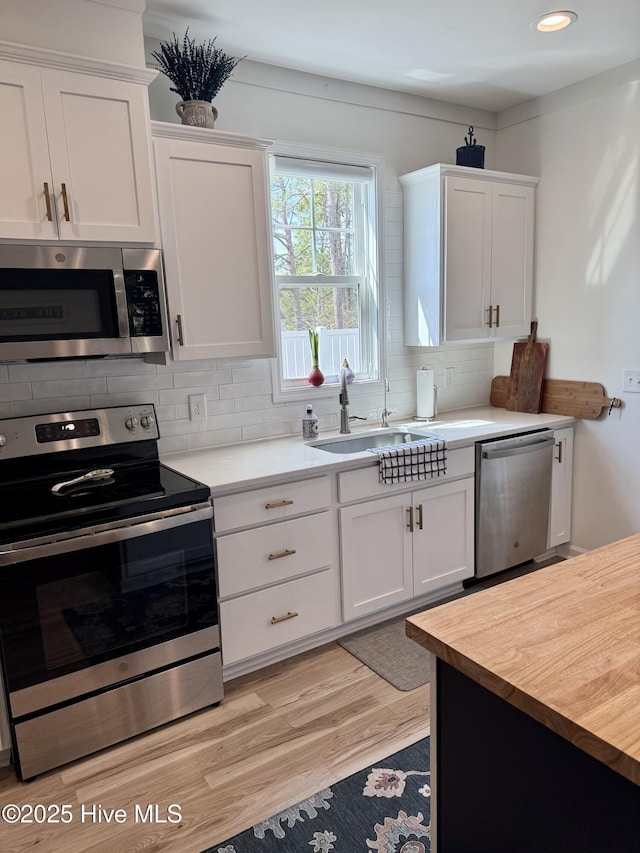 264 Great Egret Way, Beaufort, NC 28516 - kitchen featuring stainless steel appliances, a sink, decorative backsplash, white cabinets, and light wood-style flooring
