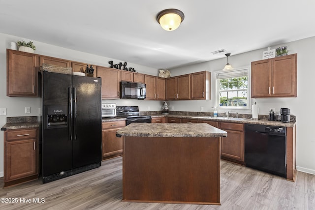 112 Silver Queen Ln, Richlands, NC 28574 - kitchen with black appliances, dark countertops, light wood finished floors, decorative light fixtures, and a kitchen island